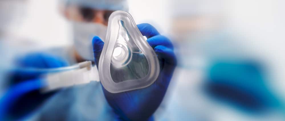 Doctor puts on oxygen mask to connect a patient losing consciousness to an artificial respiration device. Focused in oxygen mask. Emeregency and first aid concept
