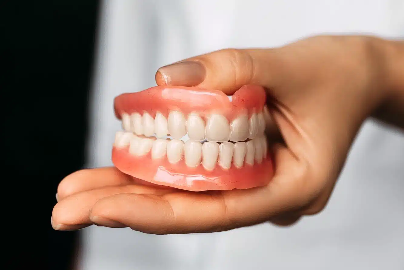 The dentist is holding dentures in his hands. Dental prosthesis in the hands of the doctor close-up. Front view of complete denture. Dentistry conceptual photo. Prosthetic dentistry. False teeth